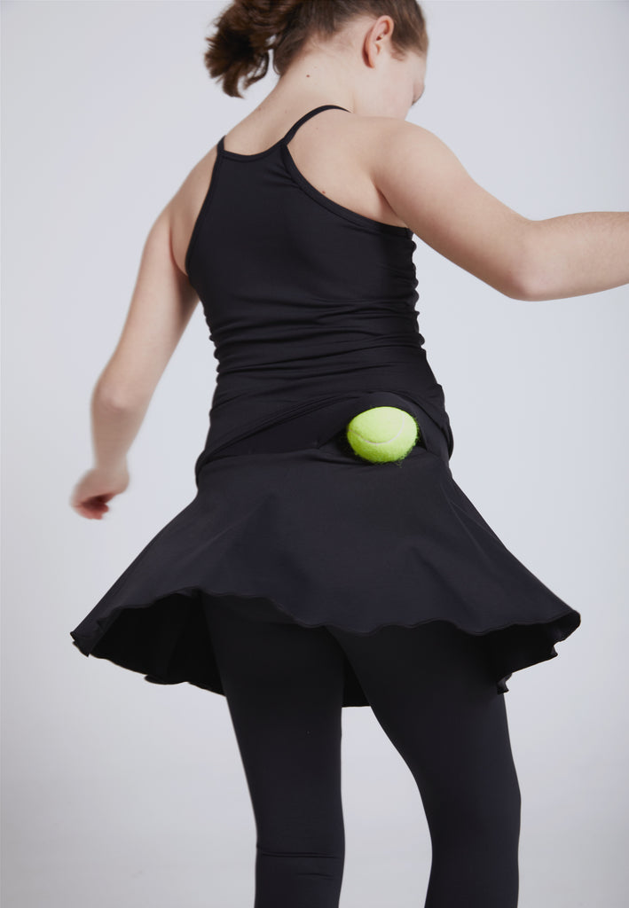 Mädchen in schwarzem tennis Outfit dreht sich